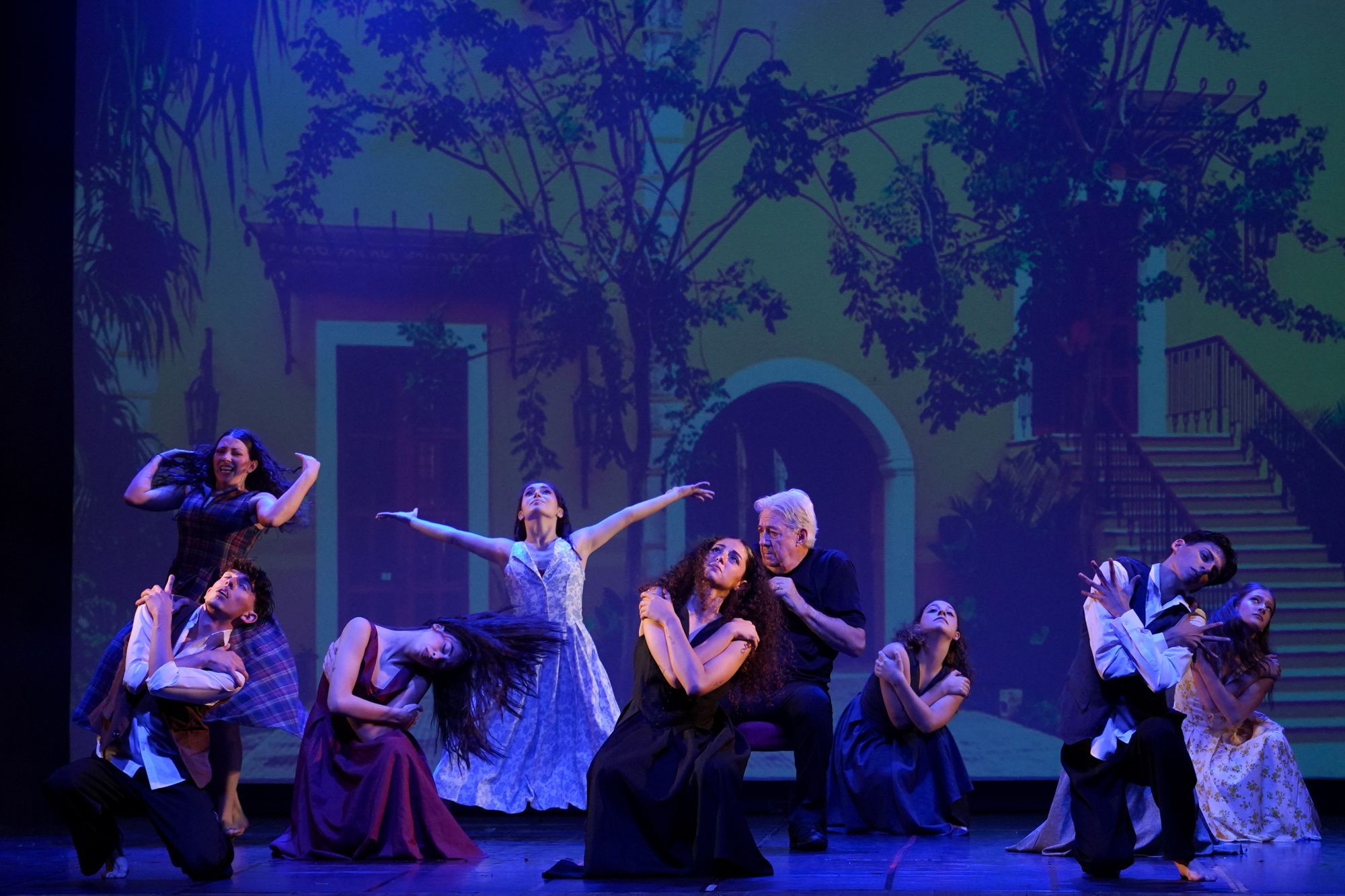 Scena corale di danza con danzatori e attore in teatro